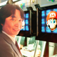 Shigeru Miyamoto in front of a screen displaying with his creation, Mario